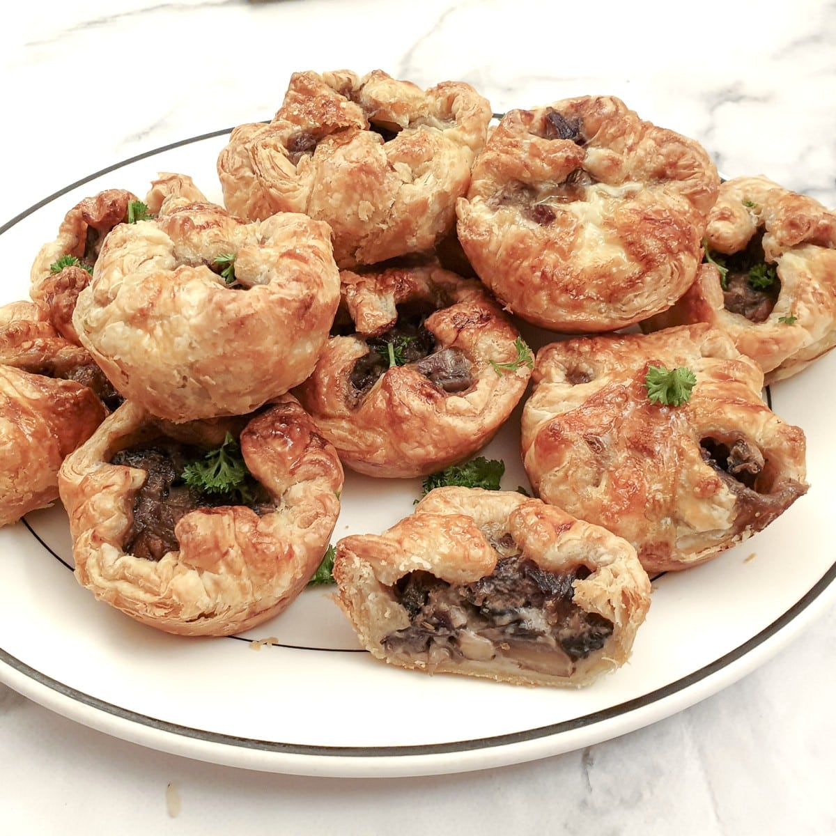 A white plate piled with mini mushroom tarts.