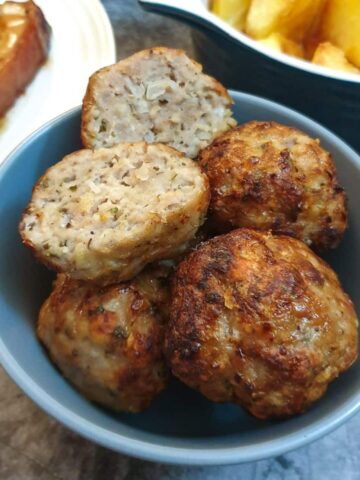 A dish of sage and onion sausage stuffing balls with one cut in half.