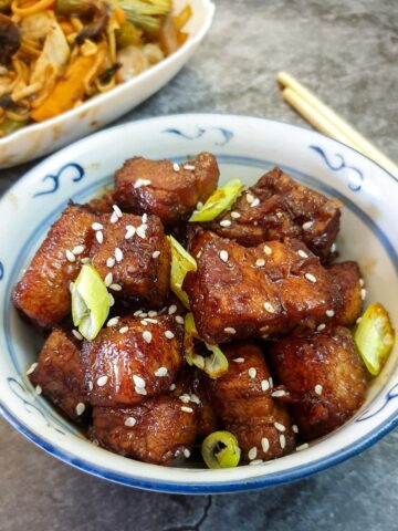 A dish of twice-cooked pork belly garnished with sesame seeds and spring onions.