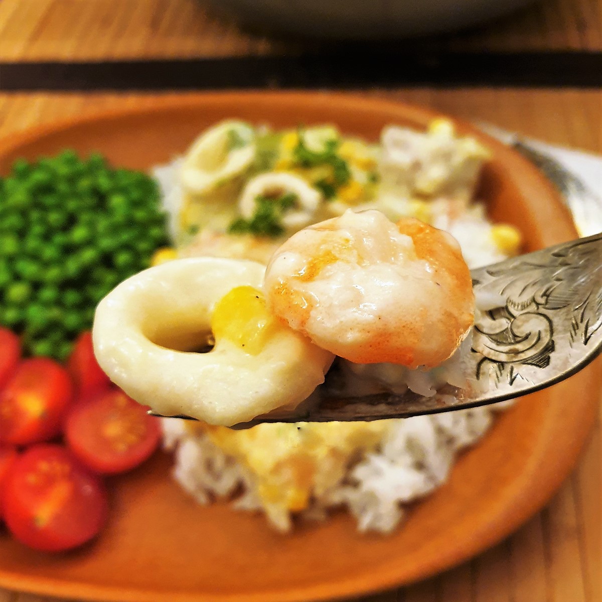 A calamari ring and a prawn on a fork.