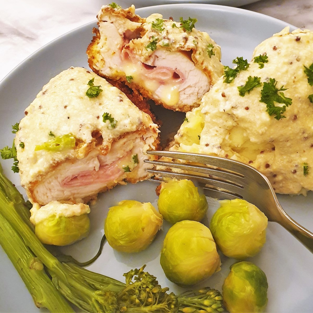 Close up of chicken cordon bleu on a plate with vegetables.