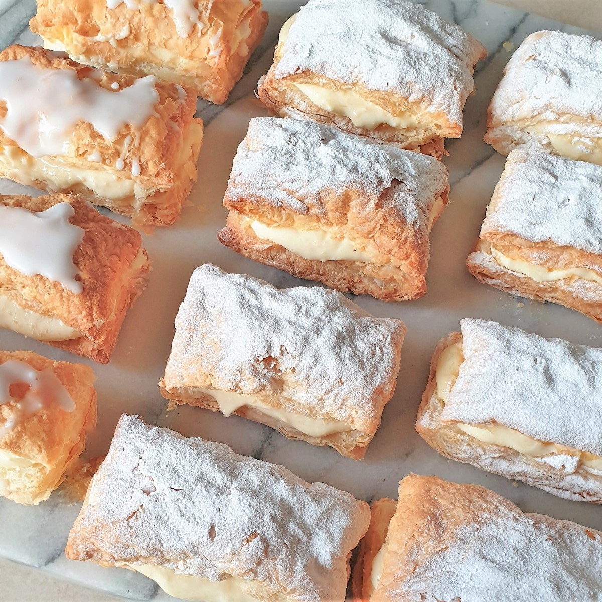 A tray of custard slices covered with icing sugar.