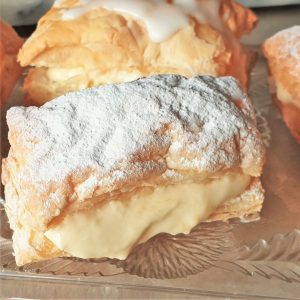 Close up of a custard slice covered with icing sugar.