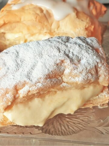 Close up of a custard slice covered with icing sugar.