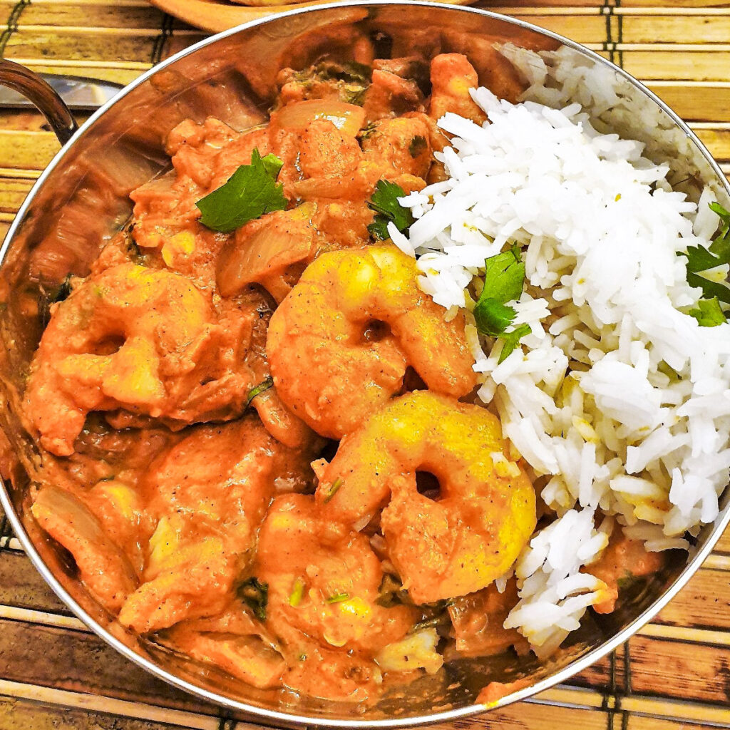A balti dish filled with kashmiri chicken and prawn curry with rice.