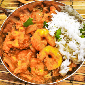 A balti dish filled with kashmiri chicken and prawn curry with rice.