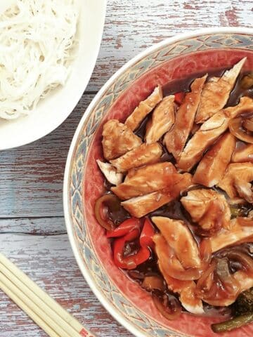 A serving dish of teriyaki chicken with a bowl of noodles.