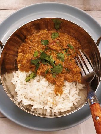A balti dish of beef madras curry with rice, garnished with chopped coriander.