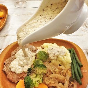 Honey mustard gravy being poured from a gravy boat.