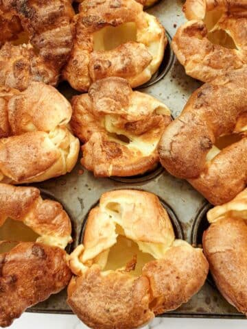 Perfectly risen Yorkshire puddings on a baking sheet.