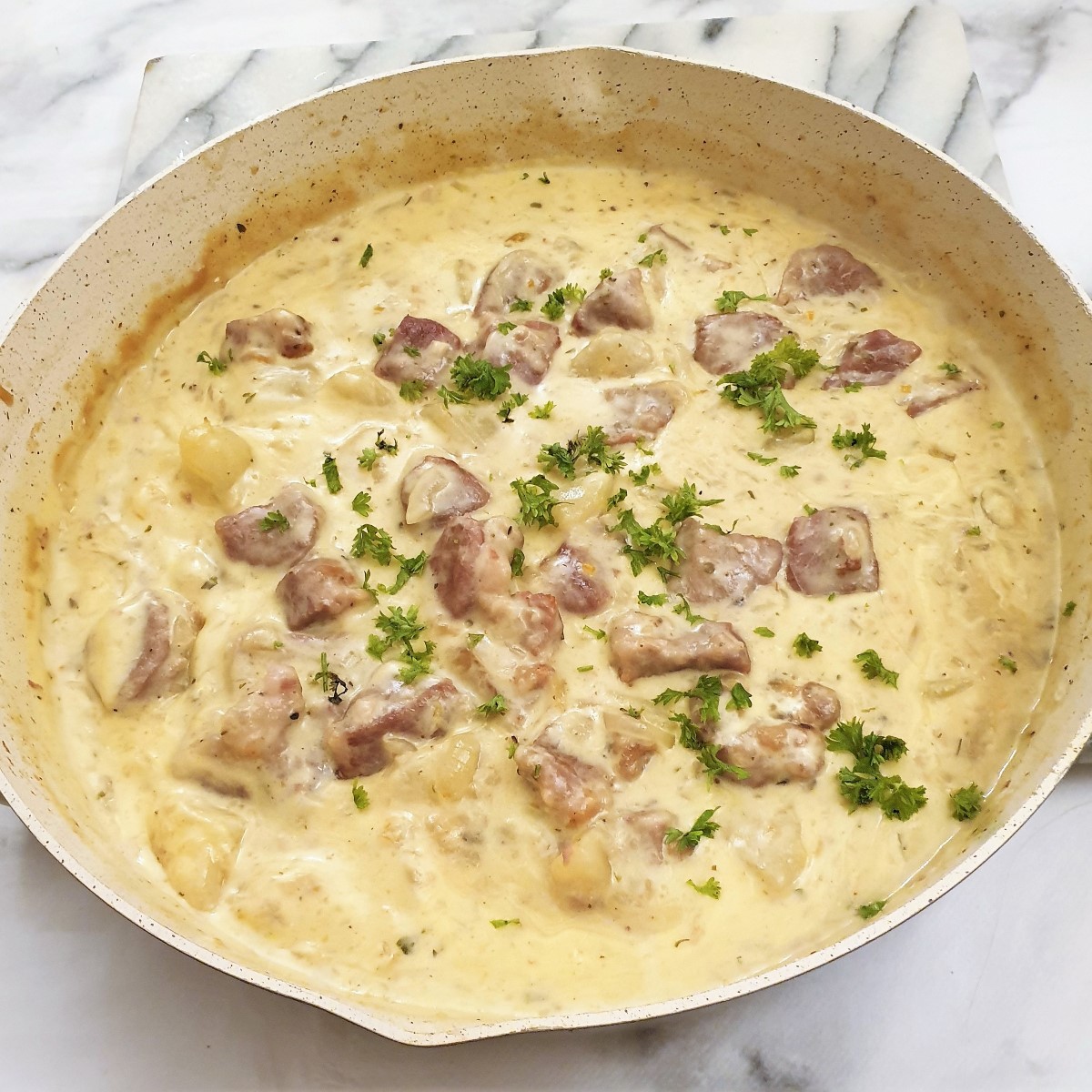 A dish of pan-fried pork and pears in a creamy sauce.