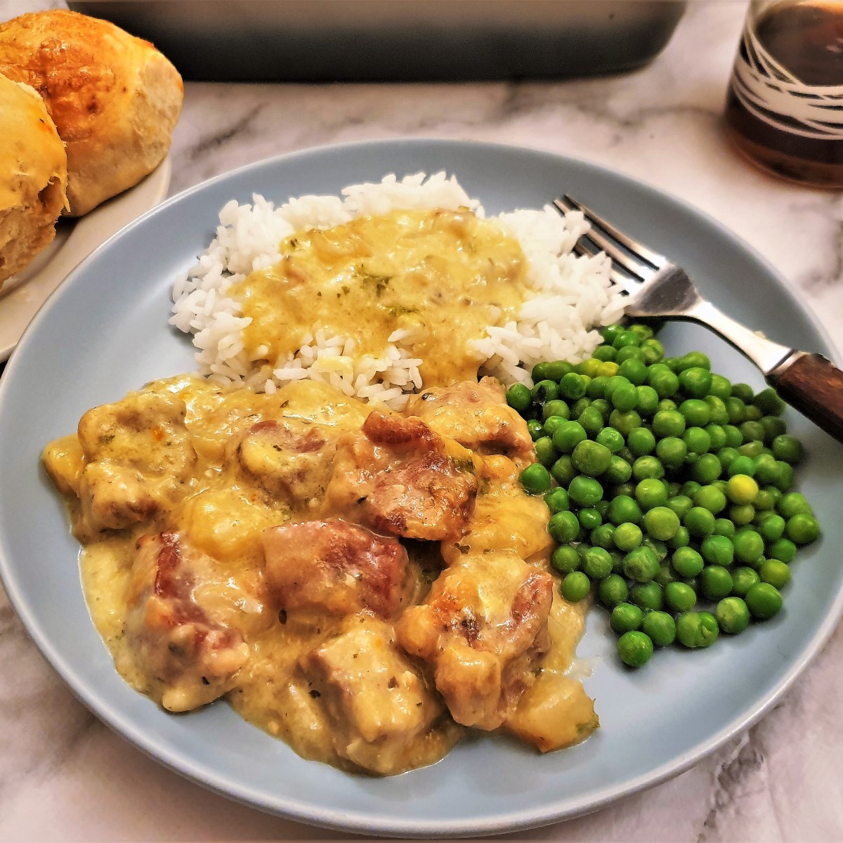 Pan-fried pork on a plate with peas, rice and gravy.