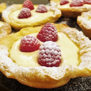 Close up of a tray of raspberry custard tarts.