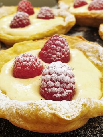 Close up of a tray of raspberry custard tarts.