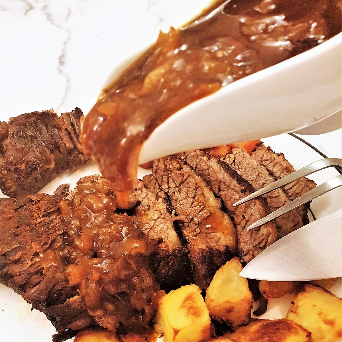 Onion gravy being poured over a plate of succulent slow-roasted brisket.