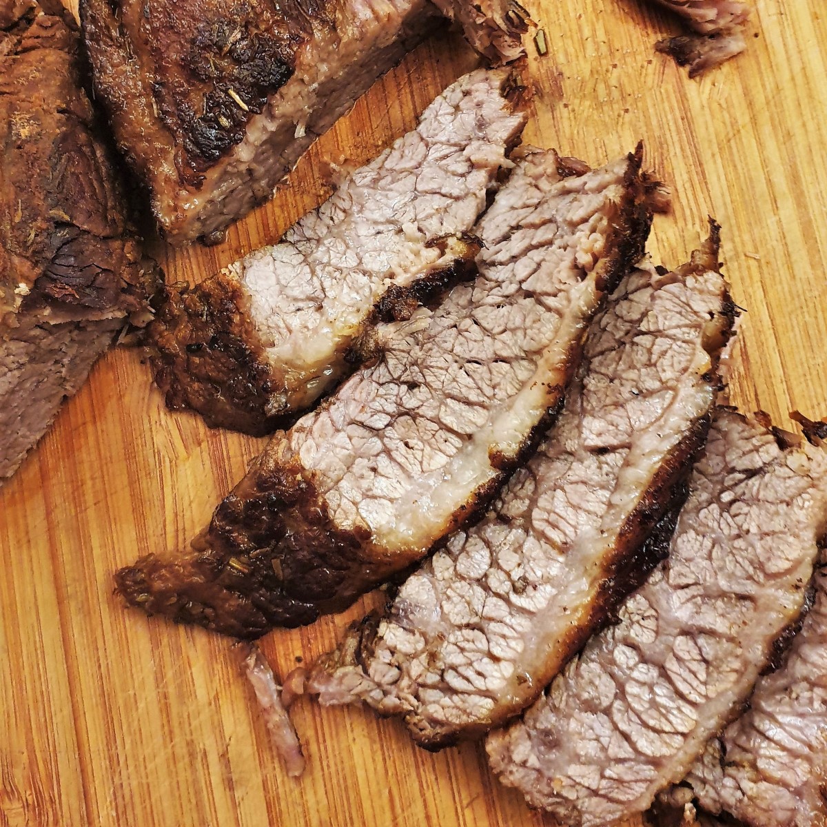 Slices of slow-roasted brisket on a wooden board.