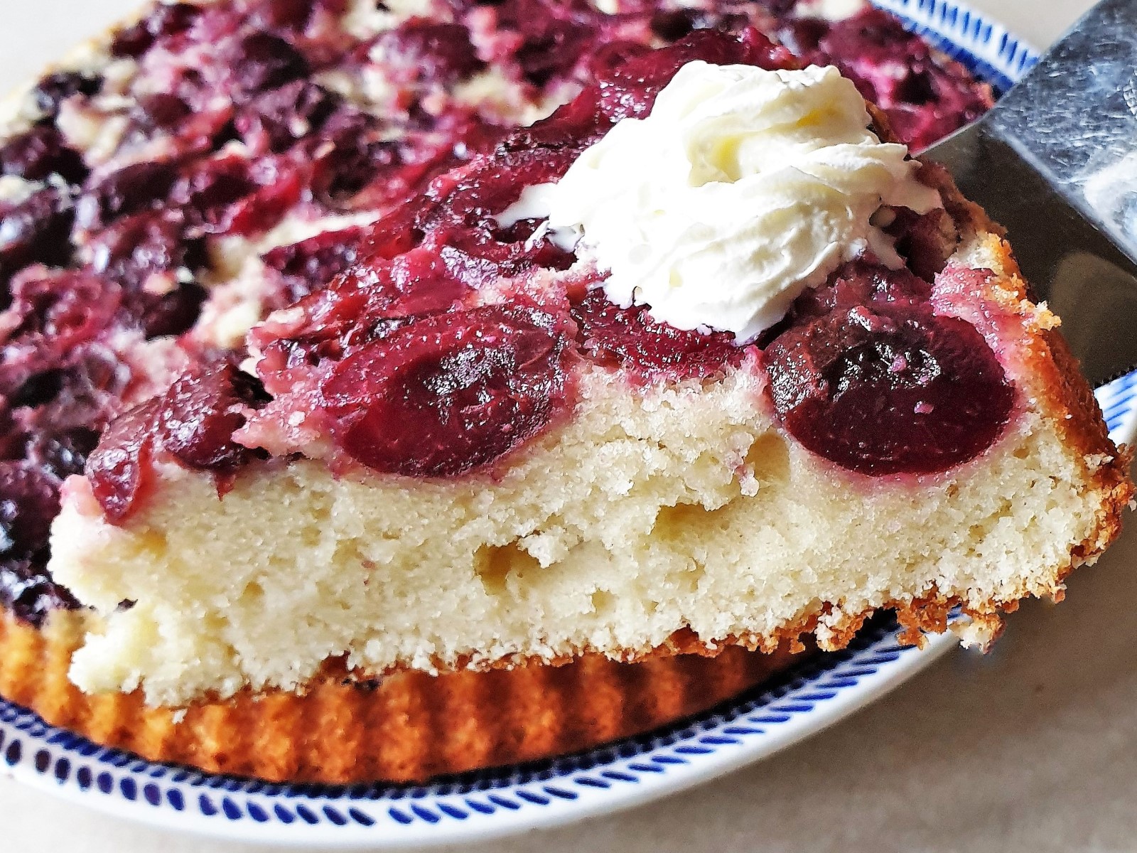 A slice of upside down cherry cake topped with whipped cream.