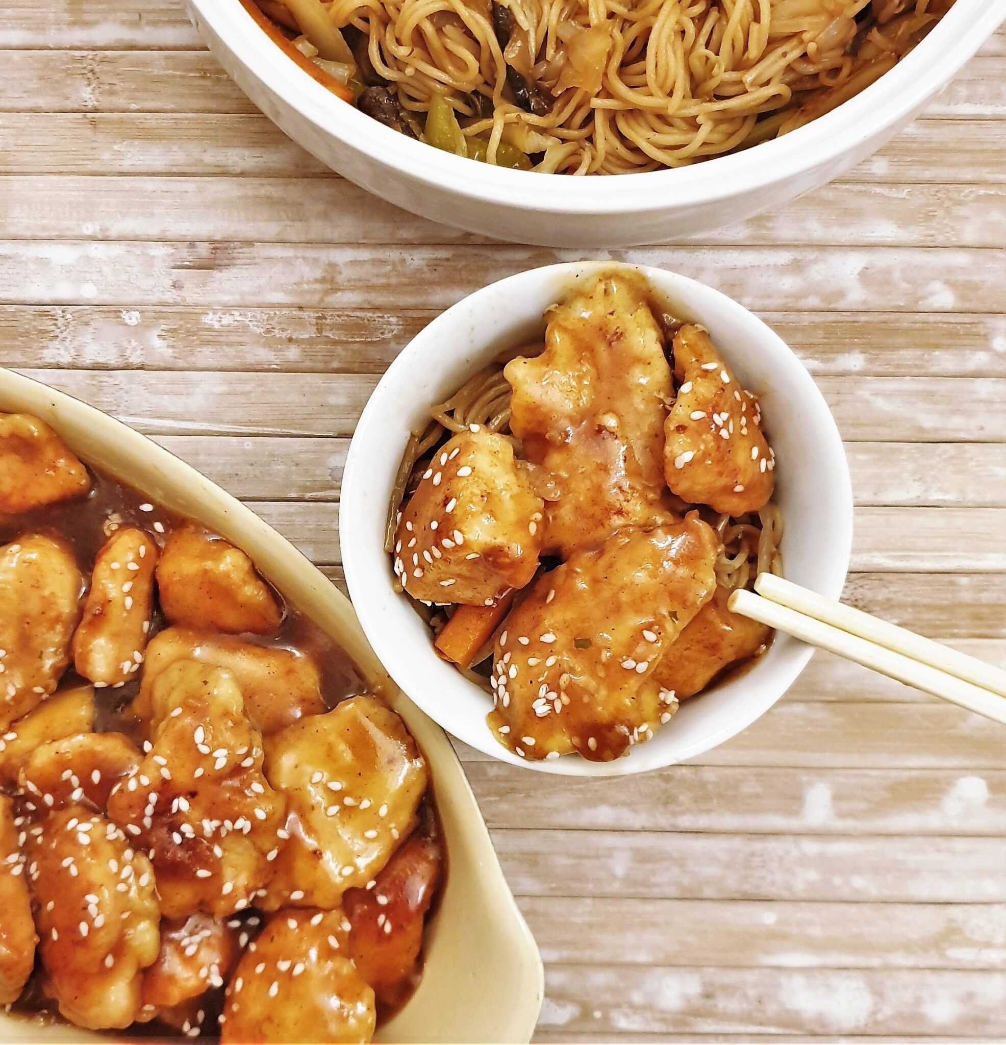 A dish of sesame chicken with chopsticks.