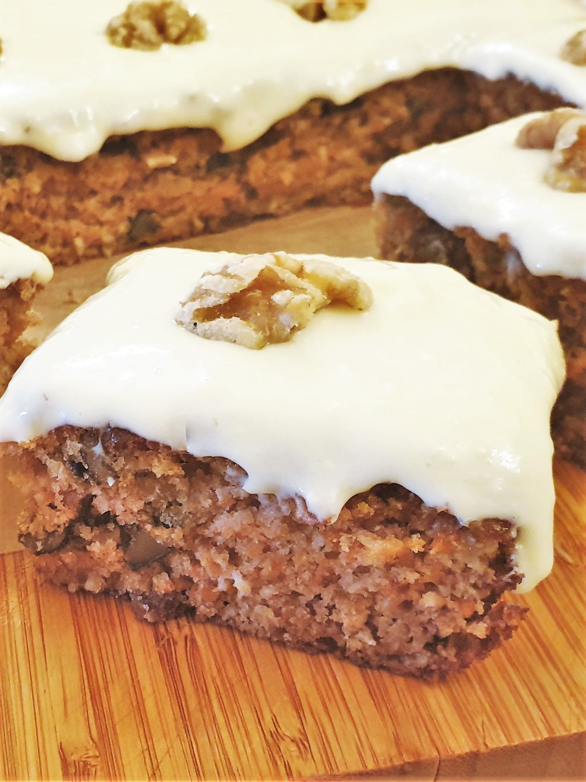 Carrot and walnut cake topped with frosting and a walnut, showing the texture.