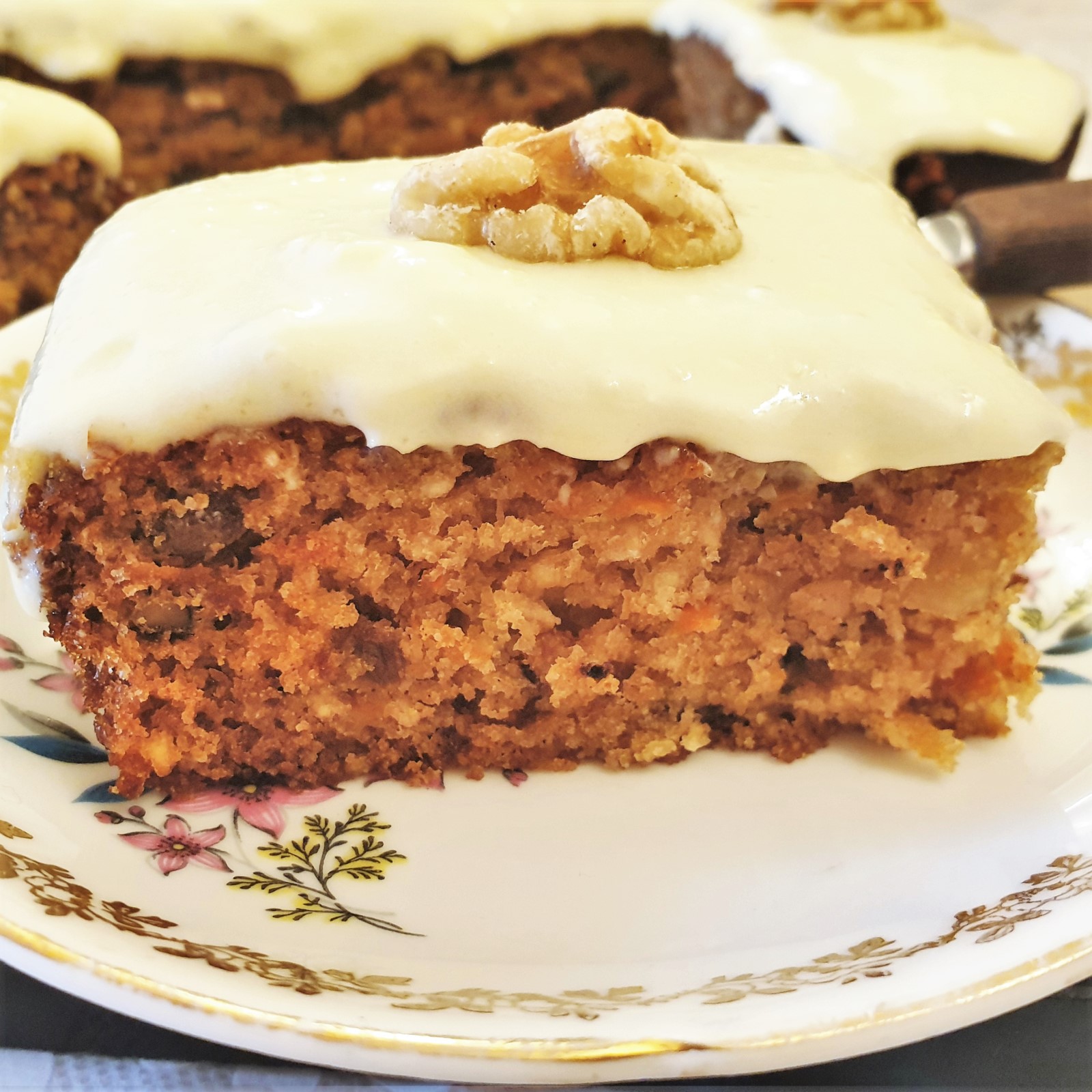 Closeup of a slice of carrot and walnut cake on a plate.