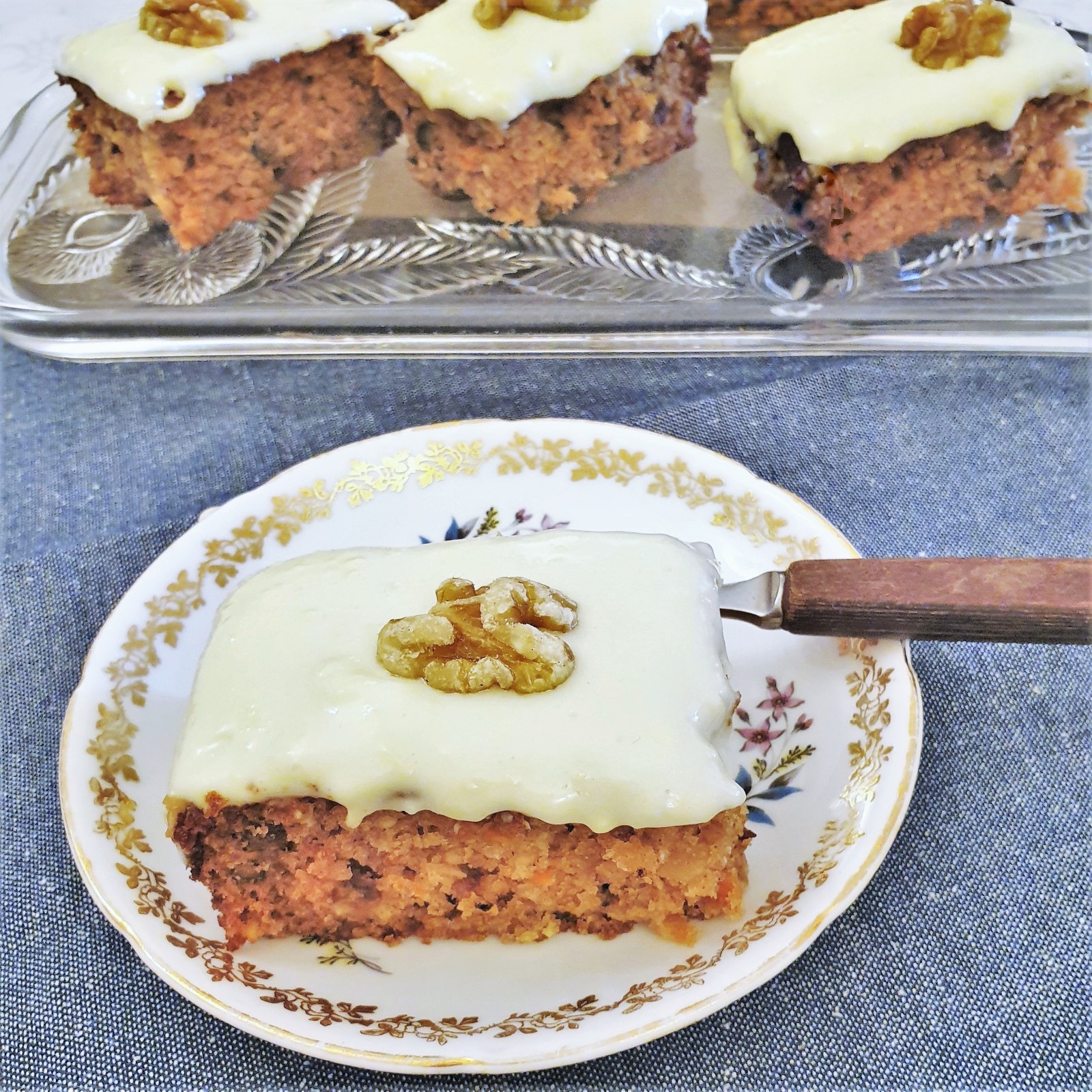 A slice of carrot cake topped with frosting and a walnut.