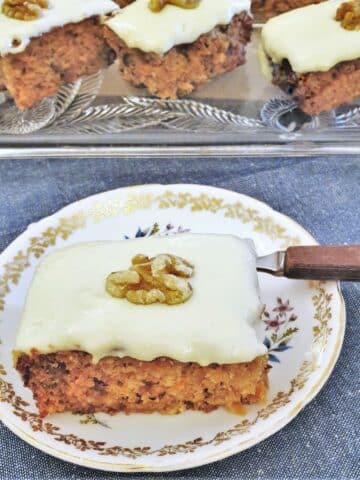 A slice of carrot cake topped with frosting and a walnut.