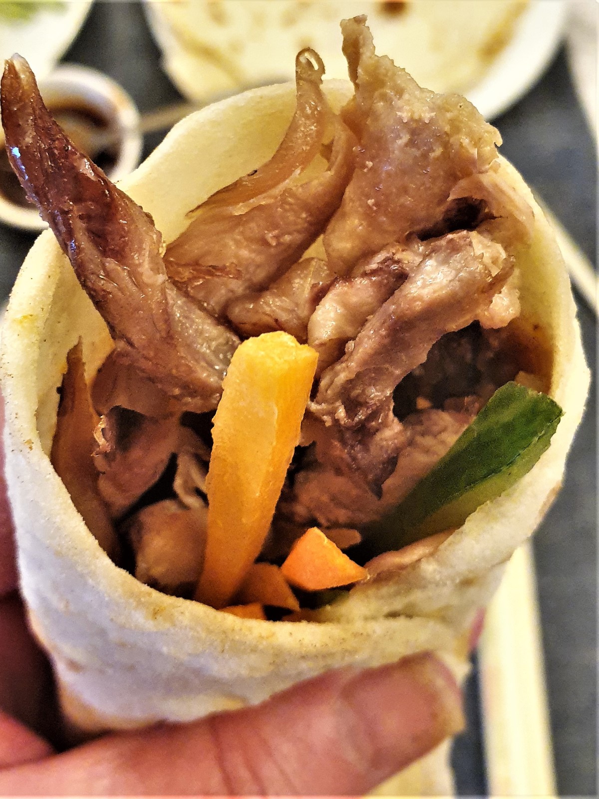 Closeup of the crispy duck inside a rolled pancake.