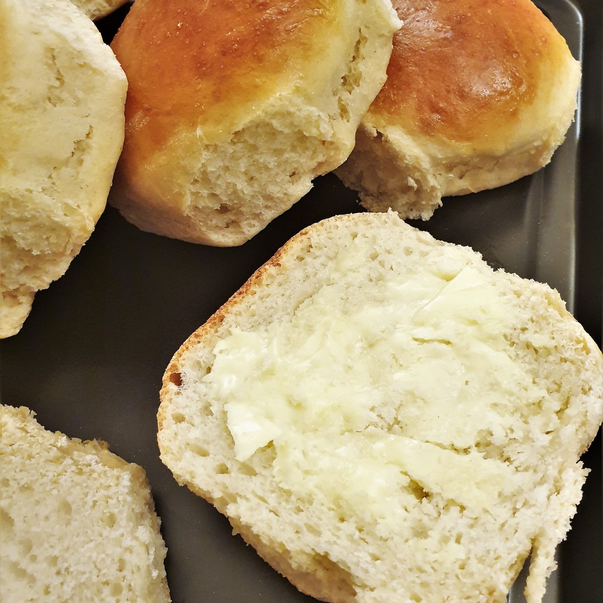 Close up of half a dinner roll spread with butter.