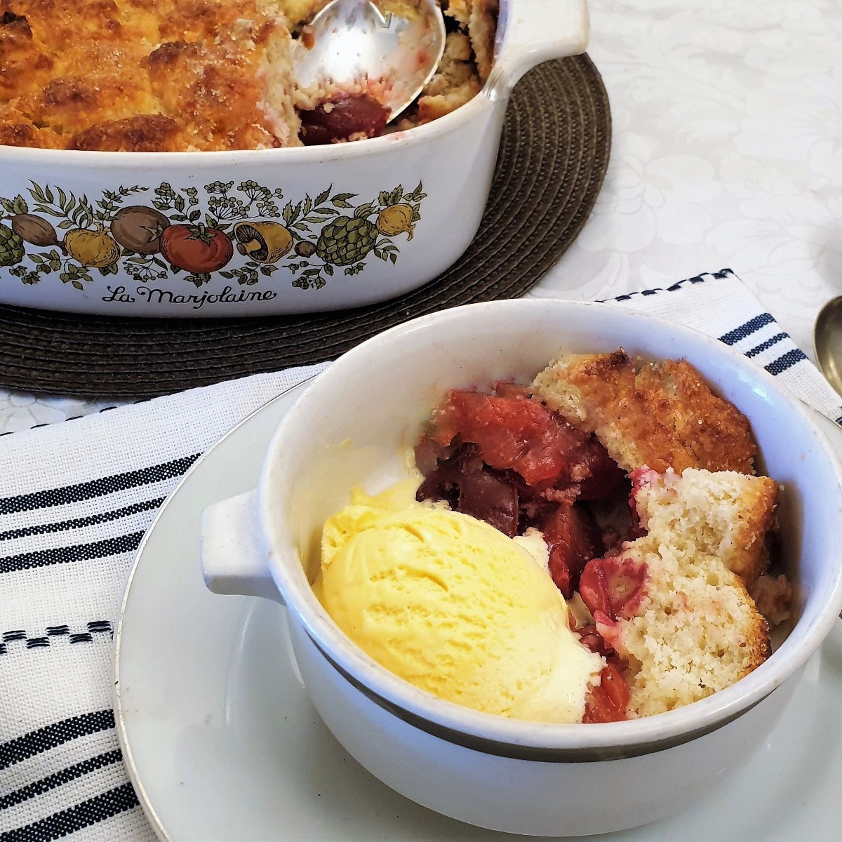 Close up of a dish of plum cobbler with ice cream.