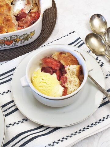 A dish of plum cobbler with a scoop of ice cream.