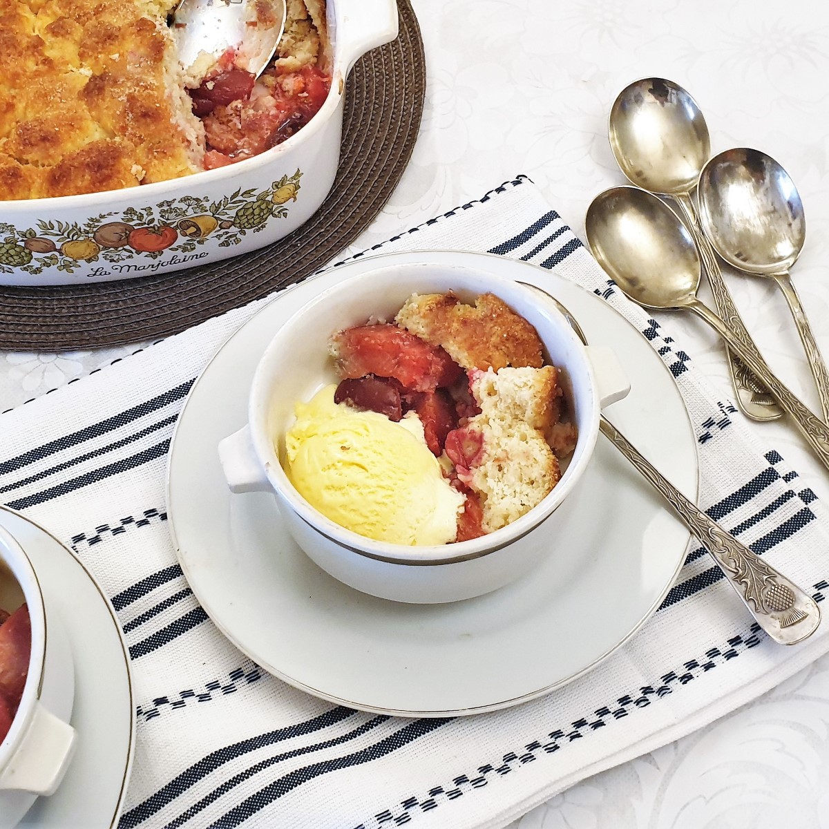 A dish of plum cobbler with a scoop of ice cream.