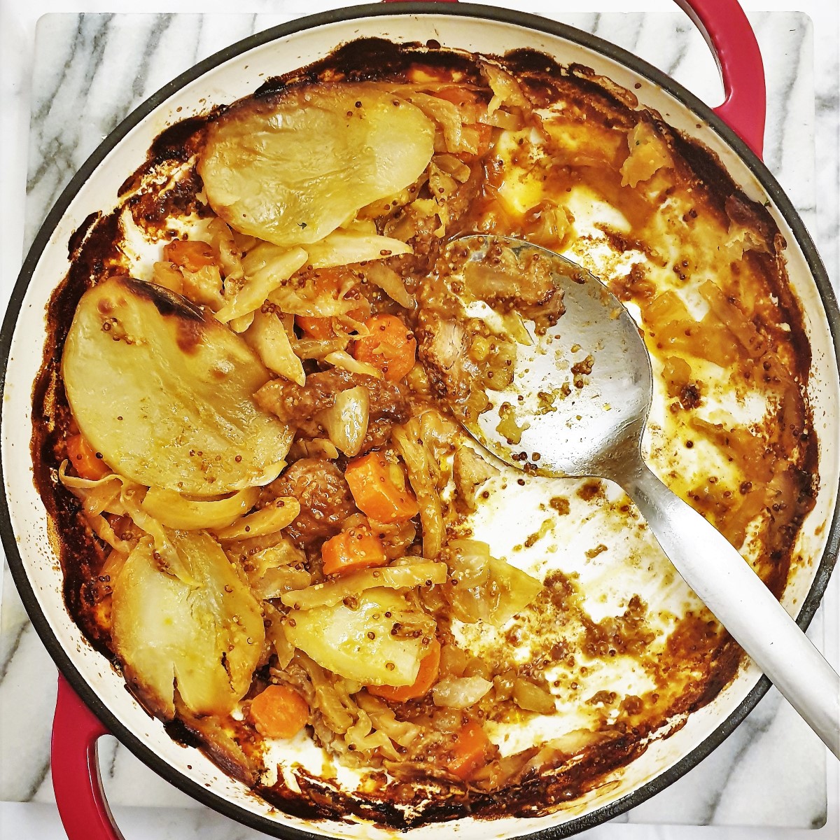 An almost empty serving dish of pork and cabbage hotpot.