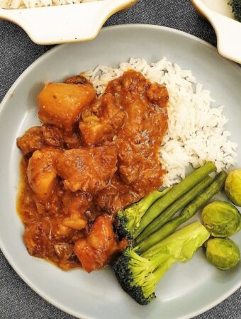 Pork casserole on a plate with rice and vegetables.