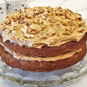 A 2-layer coffee walnut cake covered with buttercream frosting and chopped walnuts.