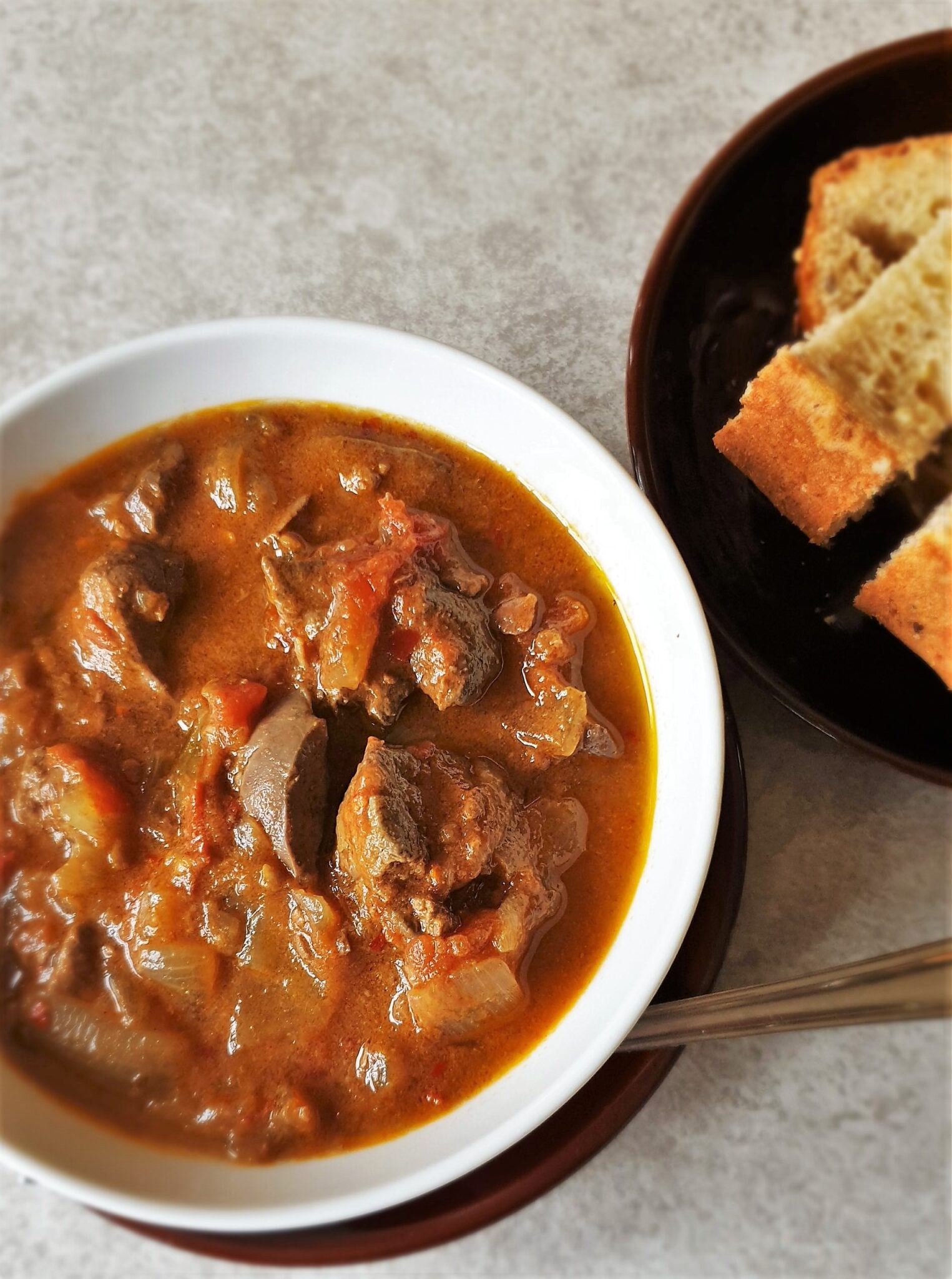 A bowl of peri peri chicken livers with crusty bread.