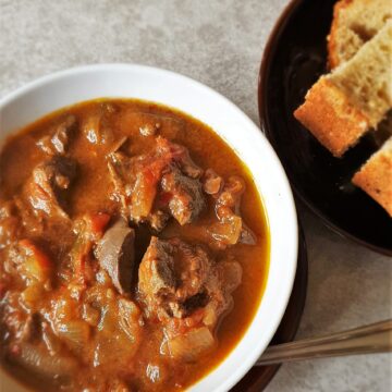 A bowl of peri peri chicken livers next to a plate of crusty bread.