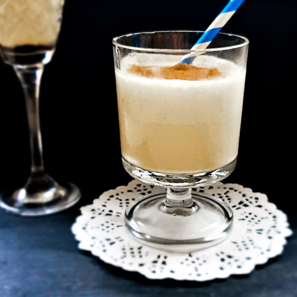 A glass of dom pedro cocktail with a blue and white straw.