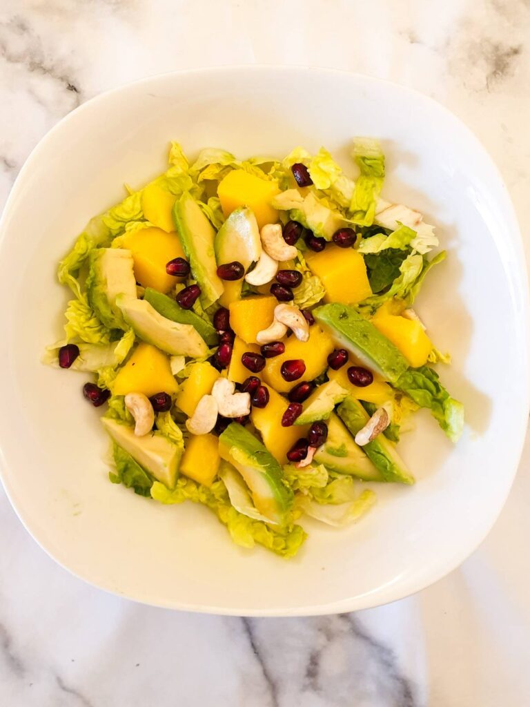 Layers of lettuce, mango and avocado sprinkled with pomegranate seeds and cashew nuts.