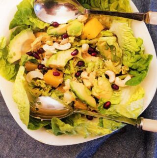 Mango and avocado salad in a bowl with serving spoons.