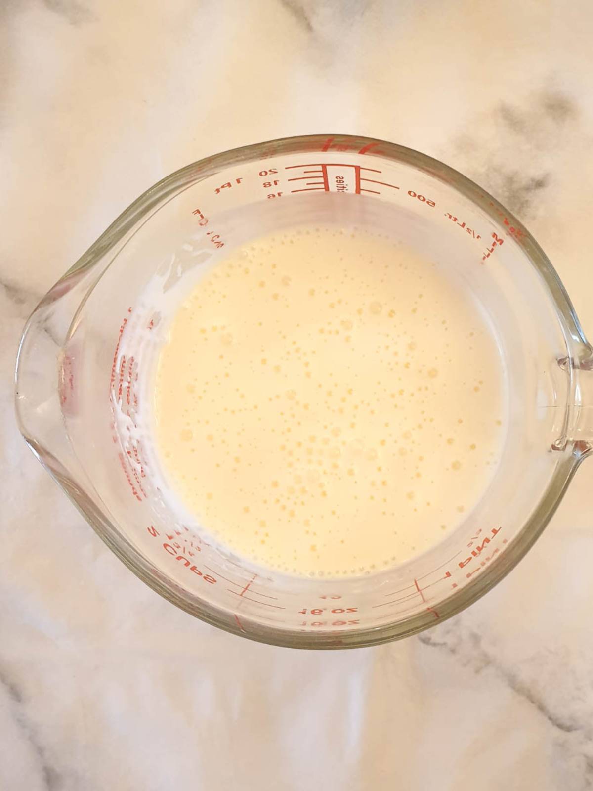 A jug of buttermilk dressing ready to be poured over the grated vegetables.