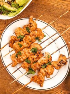 Chicken satay skewers on a plate.