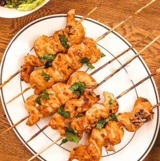 Chicken satay skewers on a plate.