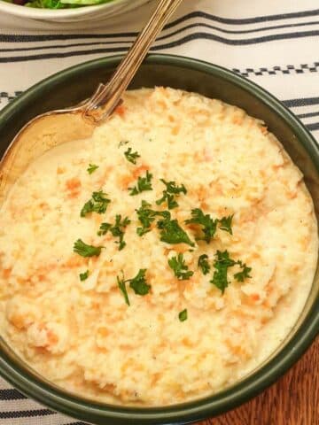 A dish of creamy coleslaw garnished with fresh parsley.