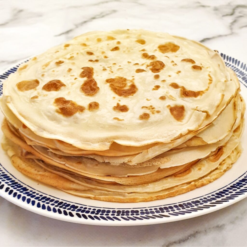 A pile of unrolled pancakes on a plate.