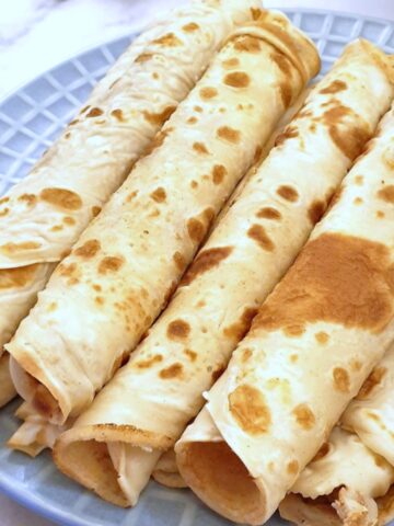 Closeup of a plate of rolled pancakes.
