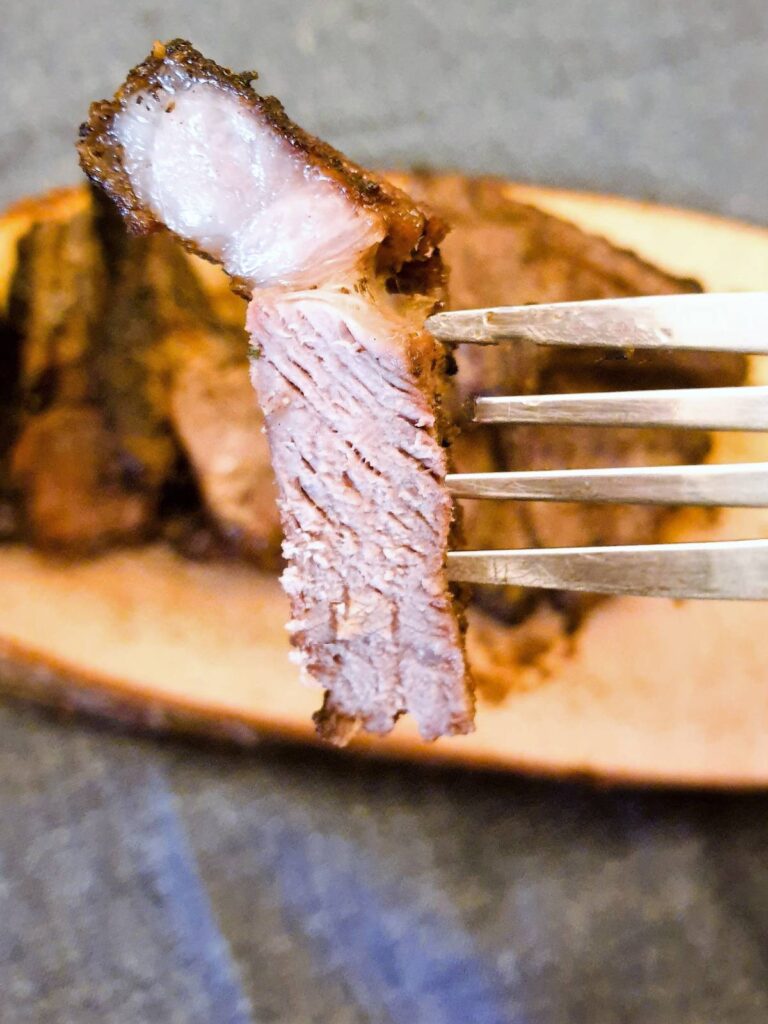 A slice of minted lamb chop on a fork.