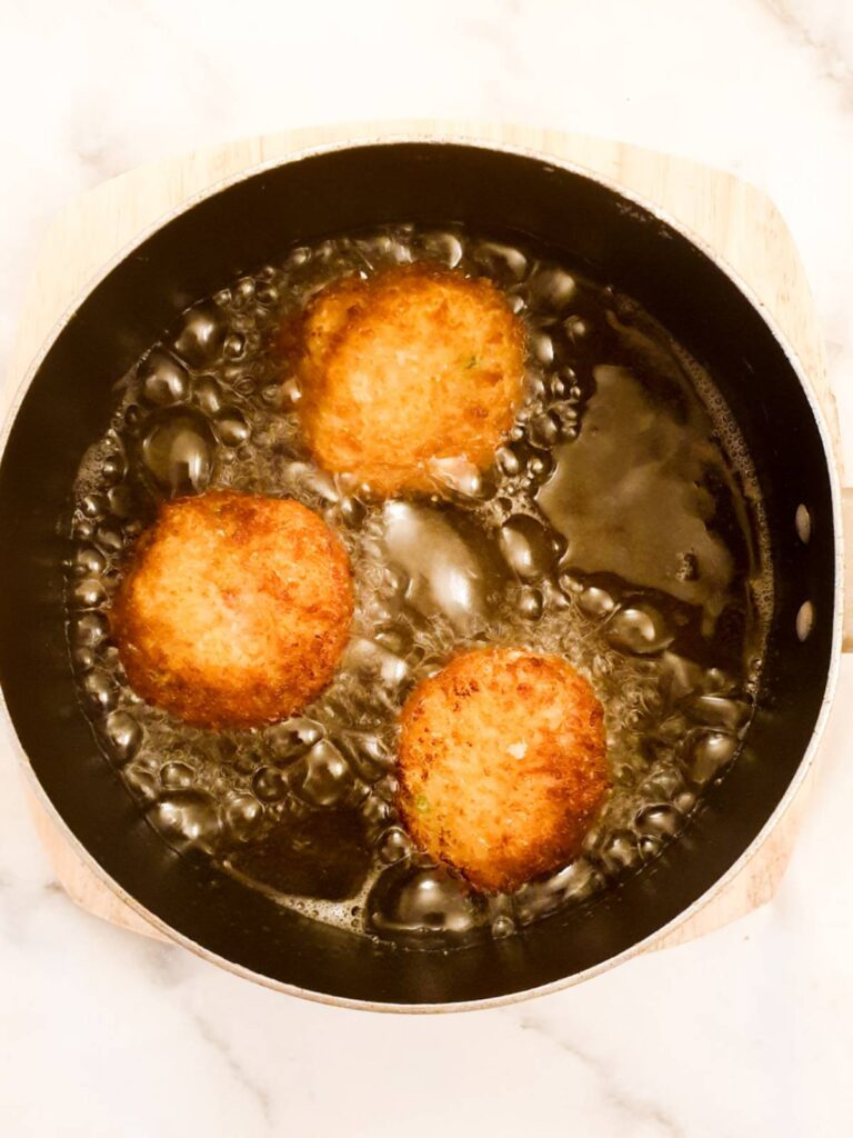 Arancini being deep fried in oil.