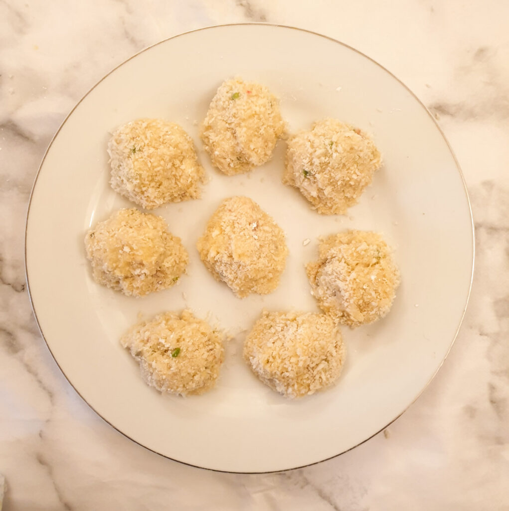 Arancini balls on a plate ready to be deep fried.