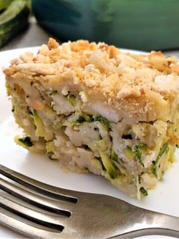 A slice of cheesy zucchini bake on a plate with a fork.