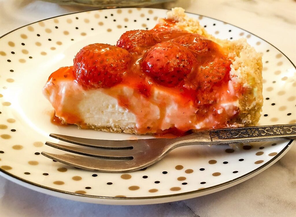 Closeup of a slice of no-bake strawberry cheesecake showing the oozy topping.